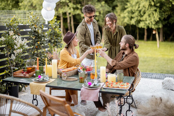 A group of young friends have delicious dinner, toasting and having great summertime together at...