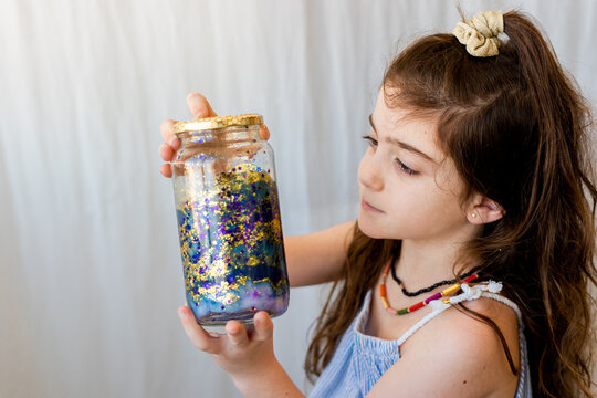 Little girl looking at glitter that she has put on her galactic pot
