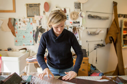 Woman cuts leather at work bench