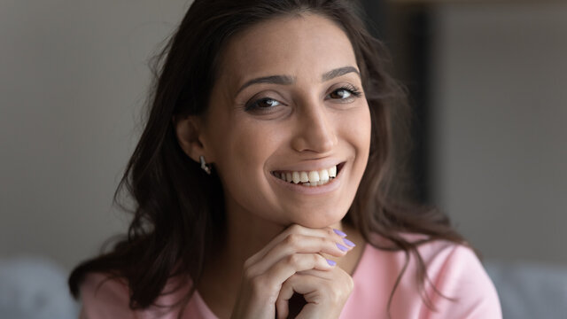 Head shot portrait positive Arabian attractive woman looking at camera, close up happy beautiful young female with healthy toothy smile and perfect smooth skin posing for photo, profile picture