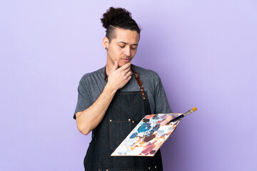 Young artist man holding a palette over isolated purple background with sad expression