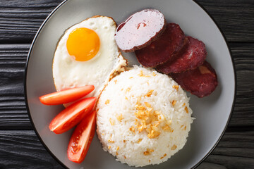 Sinangag also called garlic fried rice is a Filipino dish cooked by stir-frying pre-cooked rice with garlic close up in the plate on the table. Horizontal top view from above