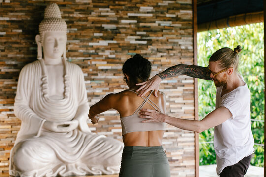 Teacher Helping Student With Postural Alignment in Yoga Class