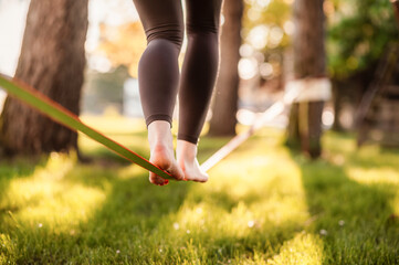 Slacklining is a practice in balance that typically uses nylon or polyester webbing. Girl walking...
