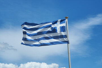 Beautiful white and blue stripes of waving Greek flag on a pole as seen on beautiful deep blue cloudscape