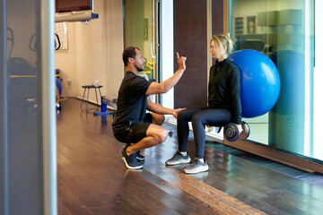 Personal trainer controlling squats with weight