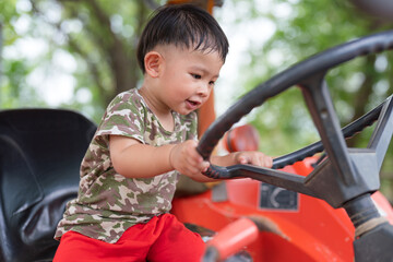 Little boy asian enjoying sitting on a tractor