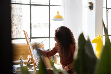 Mixed race Woman painting a picture on her home-studio.