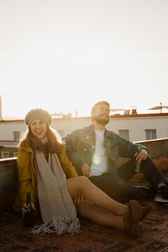 Loving ouple sitting on rootop and hugging during sunset
