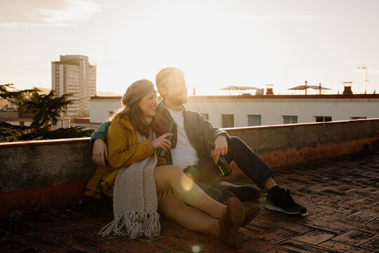Loving ouple sitting on rootop and hugging during sunset
