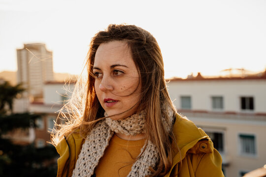 Portrait of young woman looking away on top of rooftop during susnet

