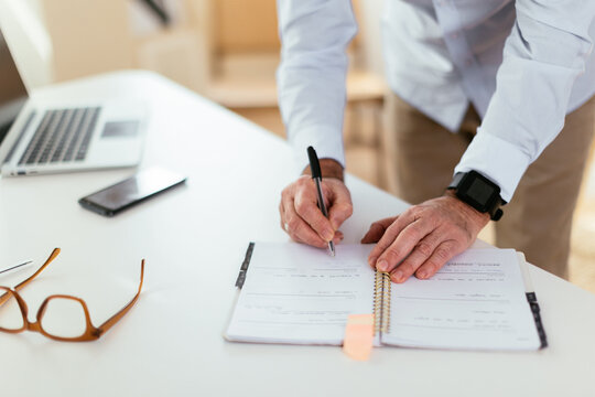 Crop employee making notes in planner