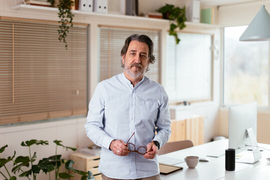 Middle aged man standing near desk in home office