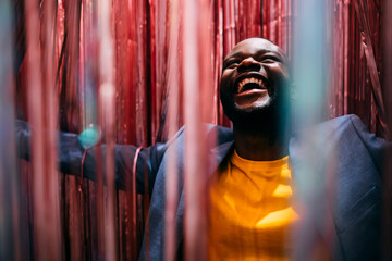A cheerful black man in party with red serpentines