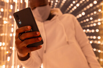 Smiling black man using smartphone in mirror labyrinth