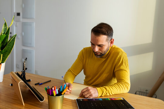 man writing note in planner at desk