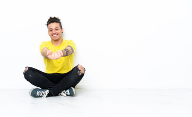 Caucasian man sitting on the floor holding copyspace imaginary on the palm to insert an ad