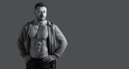 Fototapeta na wymiar Black white photo of a muscular male bodybuilder naked torso in a sports jacket on a gray background. Banner for advertising sports nutrition or fitness center.