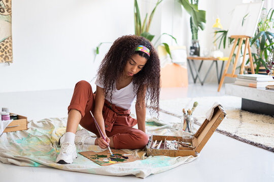 Mixed race artist woman mixing colors in a painter palette