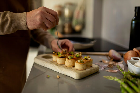 man filling fresh baked appetizers