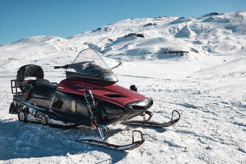 Snowmobile against snow covered slope at background. Snow vehicle 