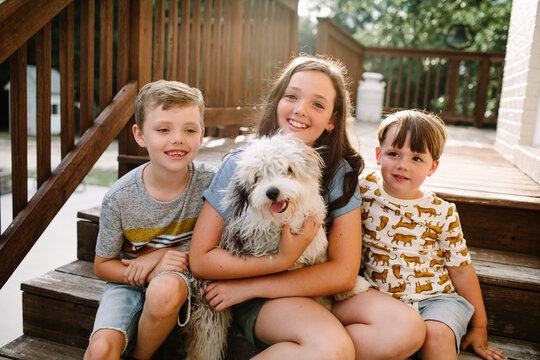 Siblings Sitting Together Outside With Dog