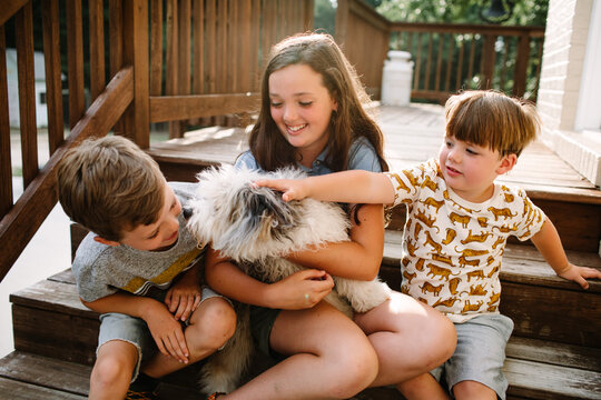 Siblings Sitting Together Outside With Dog