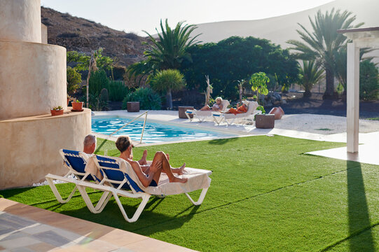 Mature people relaxing by a pool in summer