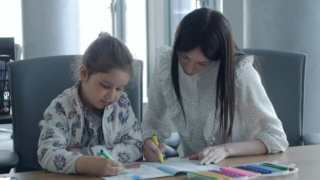 Working mom works in the office. Young woman and cute child in the office draw. Female business, kindness, care