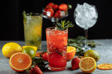 Colorful refreshing drinks for summer, cold strawberry lemonade juice with ice cubes in the glasses garnished with sliced fresh lemons