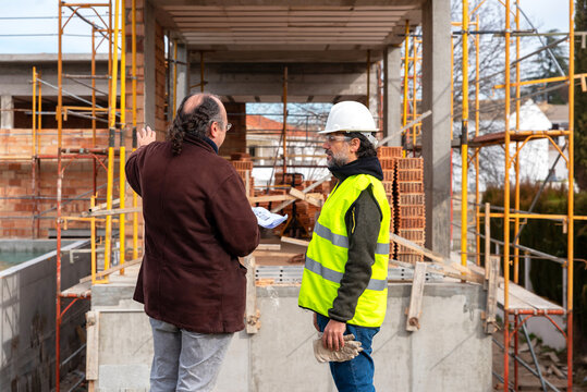 Engineer and architect discussing construction project near building