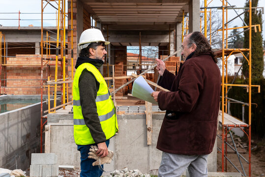 Engineer and architect discussing construction project near building