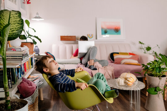 Two boys connected in different devices sharing a moment in a messy room co