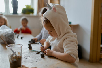 group of 5 year old preschool children in an art school learn to sculpt from clay