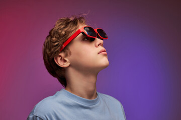 Calm teen boy wearing virtual reality goggles watching movies or playing video games,looking up at copy space. side view portrait of excited teen boy in goggles glasses for virtual reality game