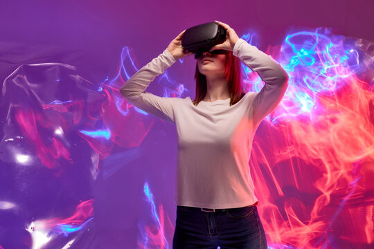 Fototapeta woman in modern wireless glasses of virtual reality against colourful 3D background, female touches the virtual world, exploring another world of reality. portrait. virtual gaming concept