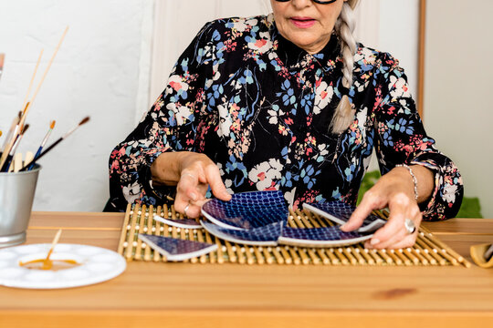 Portrait of hoary woman repairing a broken plate with a millenial japanese technique 