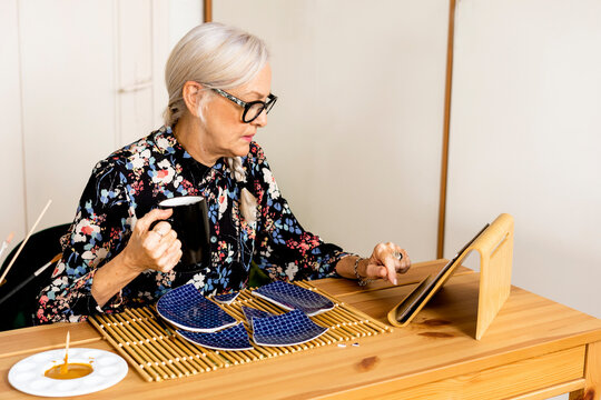 Portrait of hoary woman repairing a broken plate with a millenial japanese technique 