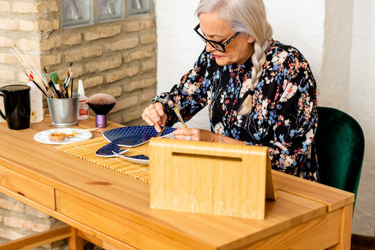 Portrait of hoary woman repairing a broken plate with a millenial japanese technique 