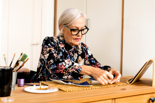 Portrait of hoary woman repairing a broken plate with a millenial japanese technique 