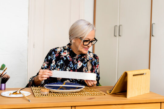 Portrait of hoary woman repairing a broken plate with a millenial japanese technique 
