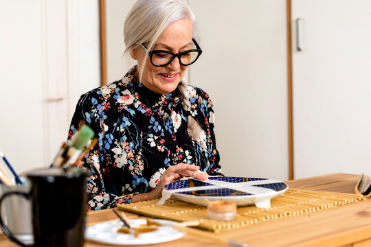 Portrait of hoary woman repairing a broken plate with a millenial japanese technique 