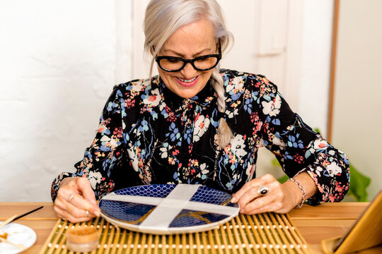 Portrait of hoary woman repairing a broken plate with a millenial japanese technique 