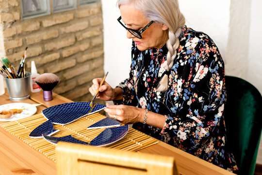 Portrait of hoary woman repairing a broken plate with a millenial japanese technique 