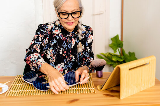 Portrait of hoary woman repairing a broken plate with a millenial japanese technique 