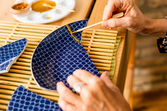 Top view of woman repairing a broken plate with gold