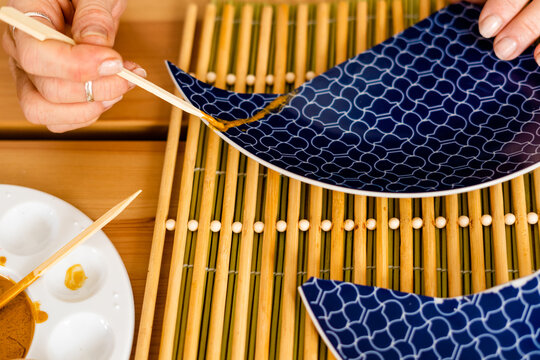 Top view of woman repairing a broken plate with gold