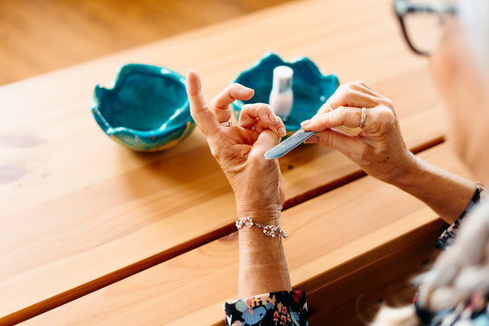 Close-up of senior woman filing her nails at home