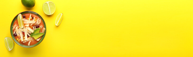 Bowl of tasty chicken enchilada soup on color background with space for text