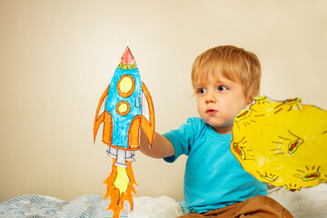 Toddler boy play astronaut holding paper rocket